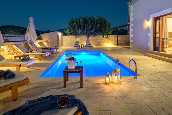 Een buitenzwembad, ligstoelen bij het zwembad