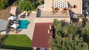 An aerial view of a modern villa with a swimming pool, outdoor seating area, and a red-roofed terrace. - Kalypso Villa, a Serene Family Retreat with Pool (Rethymno)
