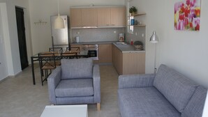 Una cocina moderna con armarios de madera, una mesa de comedor con sillas y un sofá gris en la zona de estar.