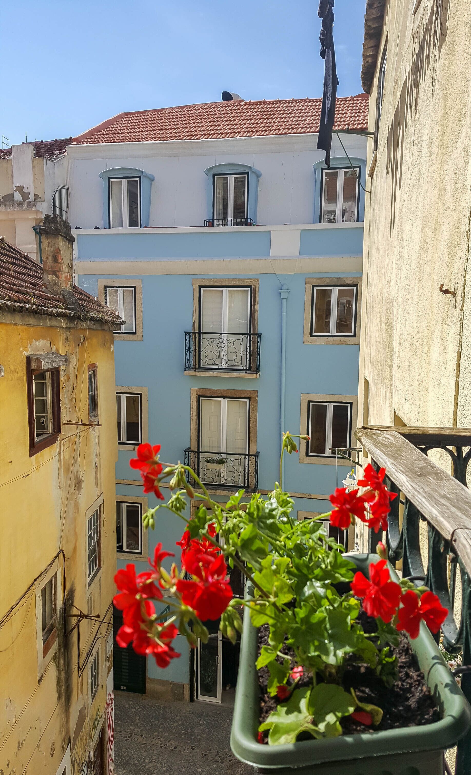 A narrow alleyway with buildings on either side, featuring balconies with railings and windows.