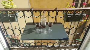 Un balcón con una mesa, dos copas de vino y una botella.