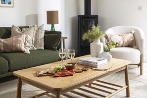 Ein Wohnzimmer mit einer Couch, einem Couchtisch, einem Bücherregal, einem Kamin und einer Lampe.