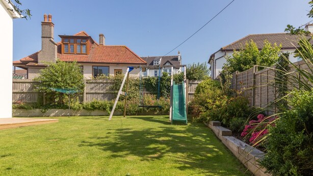Ein Garten mit Schaukel, Rutsche und einem gepflegten Rasen.