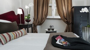 Une chambre d’hôtel avec un lit, une table de chevet, une commode et une fenêtre avec des rideaux.