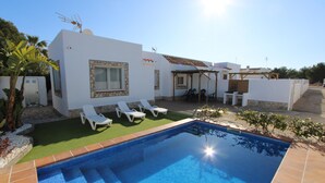 Una casa moderna amb piscina, parets blanques i zona de pati amb gandules.