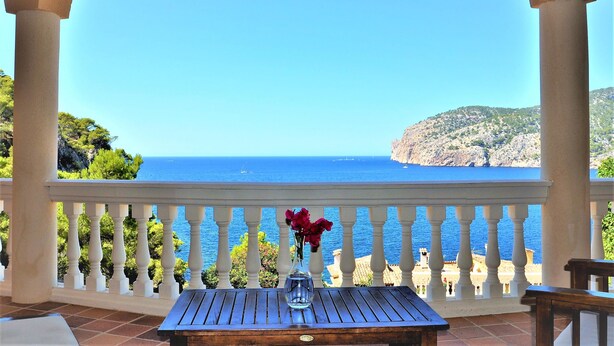 Un balcon offrant une vue dégagée sur la mer et un paysage montagneux.