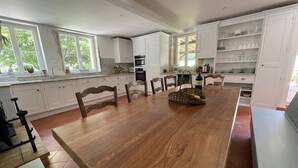 Una cocina amplia con alacenas blancas, una mesa de comedor de madera y un ventanal que proporciona luz natural.