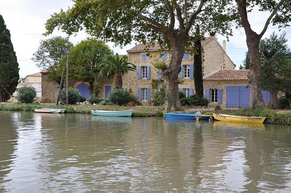 A stone building with blue shutters and a tree in front. - Very nice house with a courtyard and Wi-Fi—150 m from the beach—25% DISCOUNT IN APRIL, MAY, AND OCTOBER (VALRAS PLAGE)