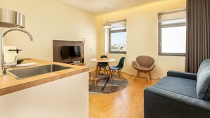 A modern kitchen with a sink, stove, and dining area with chairs and a table.