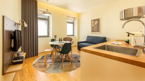 A modern kitchen with a sink, dining area with chairs, and a television.