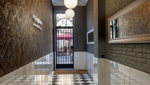 A polished hallway with a checkered floor, a metal gate entrance, and a brick wall.