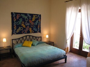 A bedroom with a bed, two bedside tables, a wall hanging, and a window with curtains. - Didyme - Comfortable flat on the beach with terrace and island views - Wifi (Lipari)