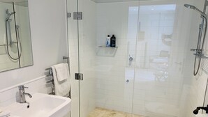 Um banheiro moderno com box de vidro, pia branca e vaso sanitário.