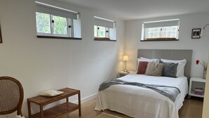 A bedroom with a bed, bedside tables, a chair, and windows.