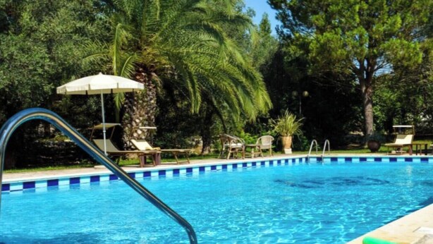 A swimming pool with clear blue water, surrounded by palm trees and lounge chairs. - Otranto: SPLENDID TENUTA WITH POOL AND TENNIS COURSE. (Muro Leccese)