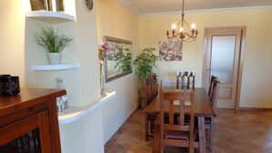 Un coin repas avec une table et des chaises en bois, un lustre et une plante en pot.
