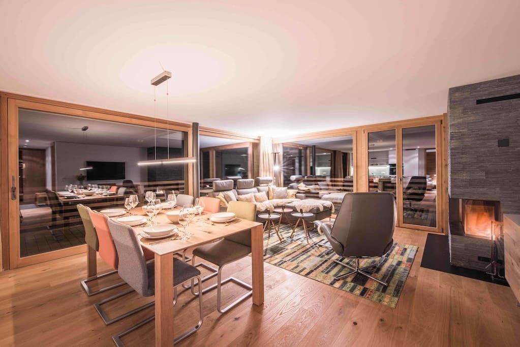 Un salon moderne avec un coin repas, de grandes fenêtres et une cheminée.
