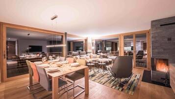 Un salon moderne avec un coin repas, de grandes fenêtres et une cheminée.