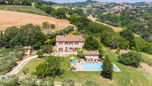 Un'ampia casa con piscina, immersa nel verde e circondata da campi.