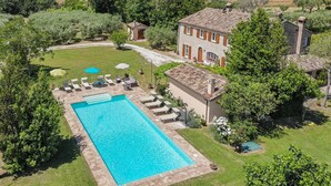 Una grande piscina rettangolare con bordo piastrellato, circondata da lettini e ombrelloni.
