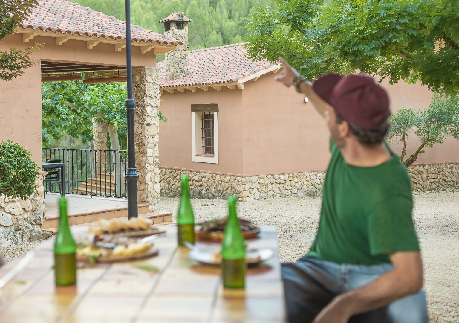 A patio with a table set for a meal, a stone wall, and a building with a tiled roof.