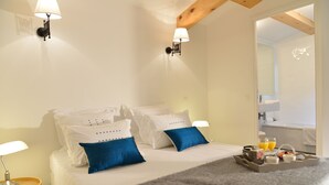 Ein Hotelzimmer mit Bett, Kissen, einem Tablett mit Frühstücksangeboten und einem durchgegangenen Tür sichtbaren Badezimmer.