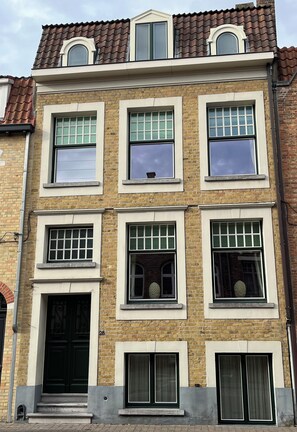 A multi-story building with a brick facade, multiple windows, and a flat roof. - 5* holiday home with Cosy Garden in the Historic Centre of Bruges (Brugge)