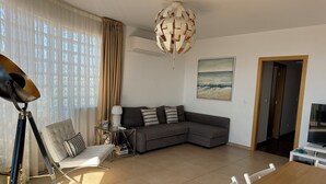 A modern living room with a sectional sofa, a dining table, and a unique spherical ceiling light. - Top Apt With Roof Terrace, Stunning 180º Atlantic Ocean and Ria Formosa View! (Fuseta)