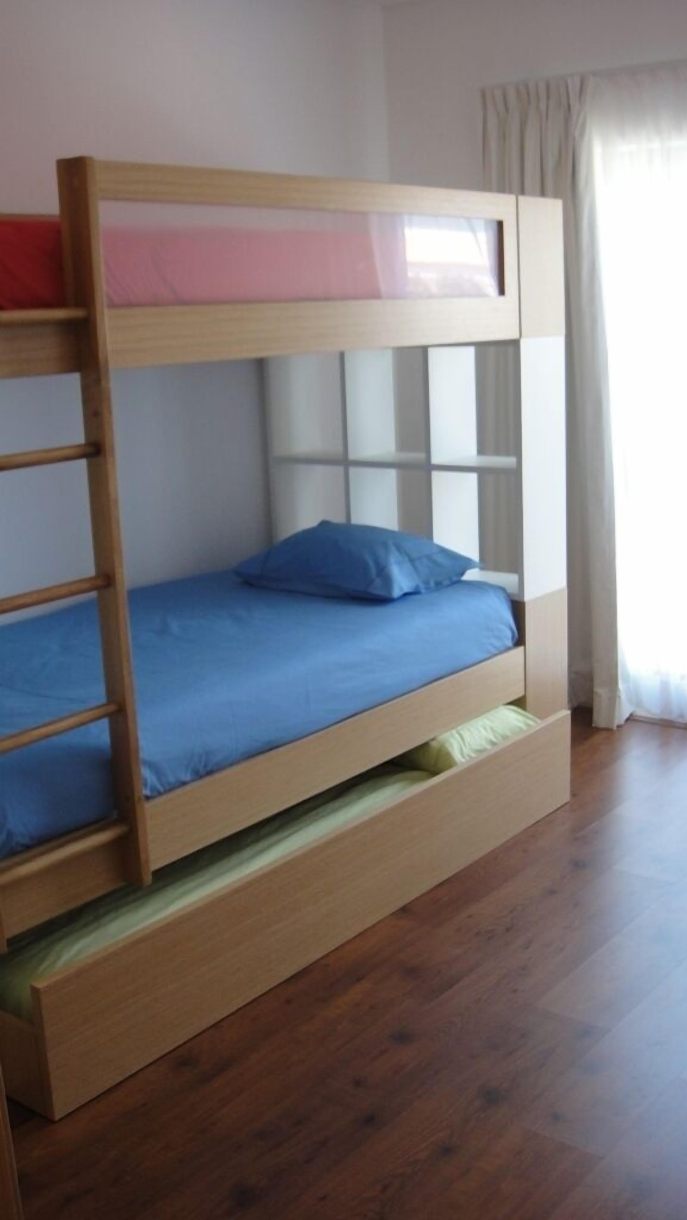 Una cama litera con estructura de madera, un colchón azul y una sola almohada azul.