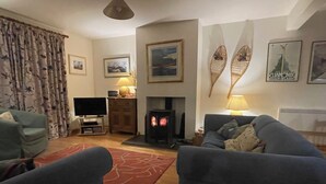 Una sala de estar con dos sofás, un televisor, una chimenea y adornos en la pared.