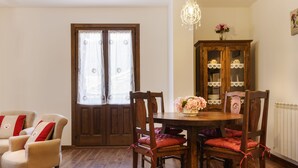 A dining area with a wooden table and chairs, a chandelier, and a cabinet with glass doors.