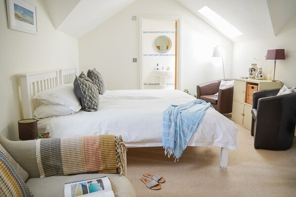 A bedroom with a bed, a desk, a chair, a lamp, and a window.