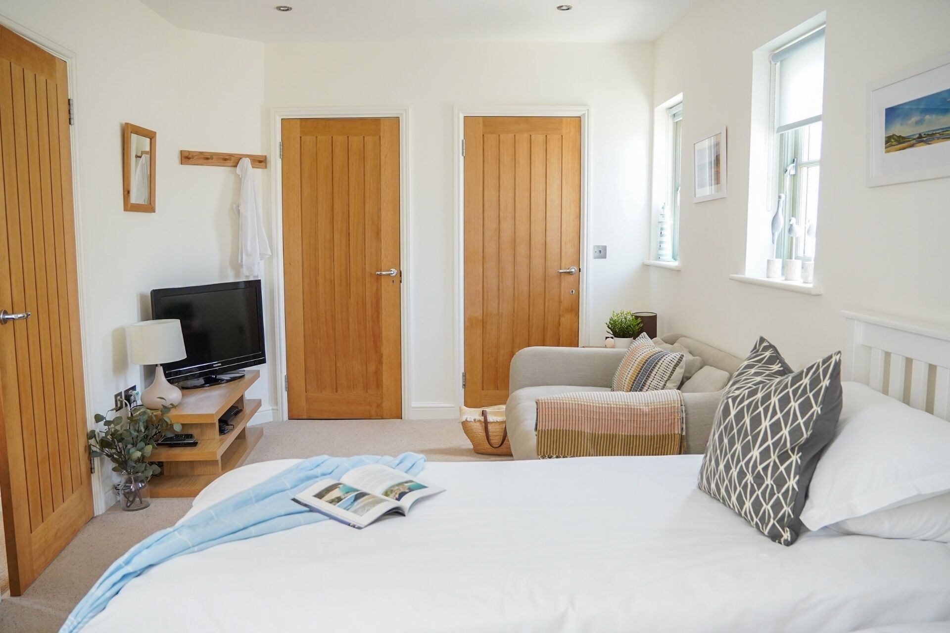 Une chambre à coucher comprenant un lit, un téléviseur, un canapé et deux portes en bois.
