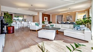 Un vaste espace de vie comprenant un canapé blanc, une table basse et un coin repas avec des chaises.