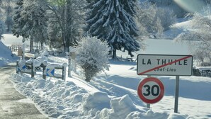 Una carretera cubierta de nieve con un cartel de límite de velocidad y un letrero que indica 'La Thuille Chef-Lieu'.