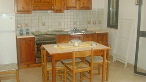 A kitchen with wooden cabinets, a tiled backsplash, a stove, and a table with chairs.