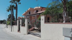 A two-story house with a gated entrance, satellite dish, and a number '12' on the wall.