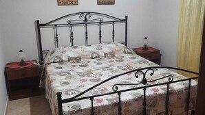 A bedroom with a bed, two bedside tables, a lamp on each table, and two wall-mounted pictures.