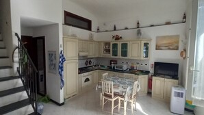 Eine Küche mit Esstisch, Schränken, einem Herd, einer Mikrowelle und einem Kühlschrank.