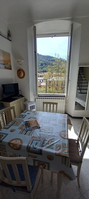 Un comedor con una mesa preparada para dos, un televisor y vistas a una ladera.