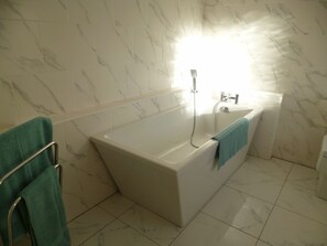 Un baño con una bañera grande, ducha e inodoro.