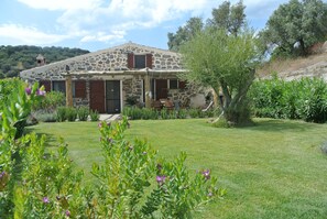 A stone house with a sloped roof, a wooden door, and a small porch area.