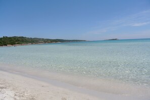 A beach with clear turquoise water, sandy shore, and a distant island. - DREAM LOCATION in SARDINIA: stunning private hunting lodge minutes from beach (Orosei)