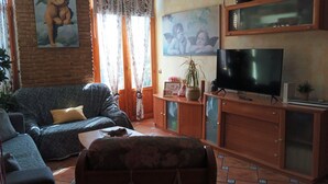 Una sala de estar con un sofá, un televisor, un mueble y un cuadro en la pared.