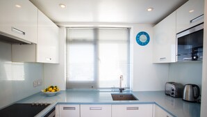 A modern kitchen with a blue countertop, a sink, a stove, and a toaster. - Stunning Seafront Penthouse w/ Private Sun Terrace & Direct Panoramic Sea Views (Kings Road)