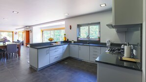 A modern kitchen with a central island, built-in appliances, and large windows offering natural light.