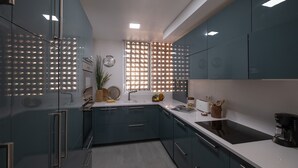 Una cocina moderna con armarios azul oscuro, encimera blanca y un separador de vidrio con un diseño luminoso.