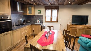 Una cocina moderna con armarios de madera, una mesa de comedor con mantel rojo y un televisor en la sala de estar.