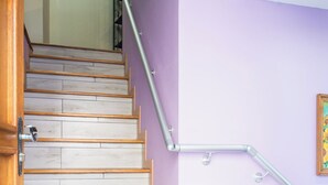 Una escalera de madera con barandilla de metal, que lleva a un rellano con alfombra estampada.