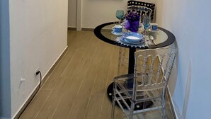 Un comedor con una mesa redonda, sillas, una araña y dos cuadros en las paredes.